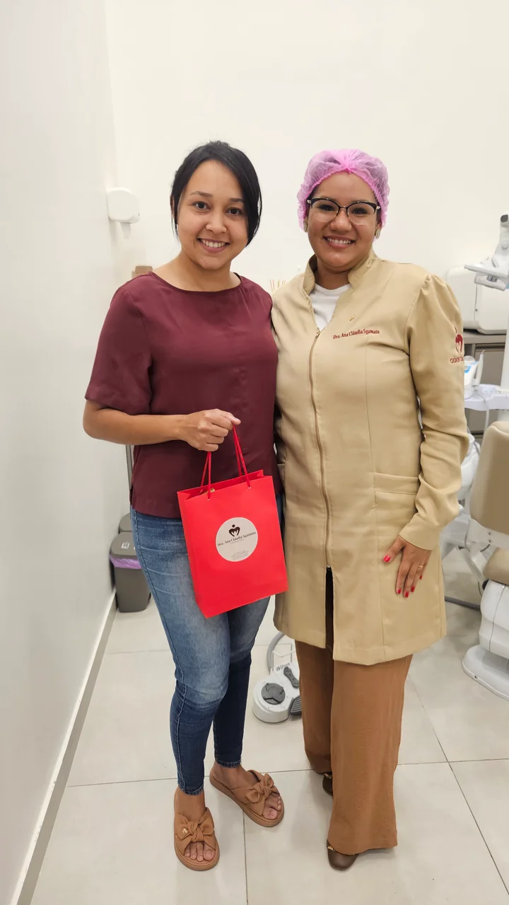 Dra. Ana ao lado de uma paciente no consultório, ambas sorrindo