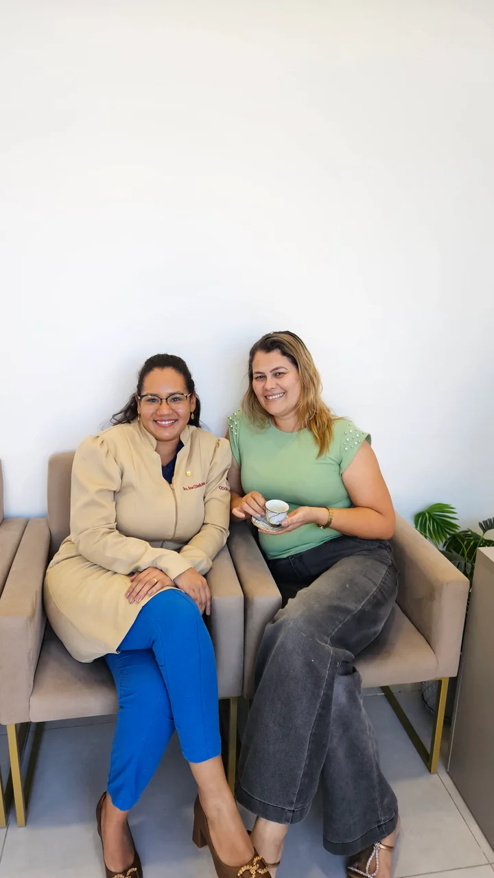 Dra. Ana sentada ao lado de uma paciente na recepção da clínica